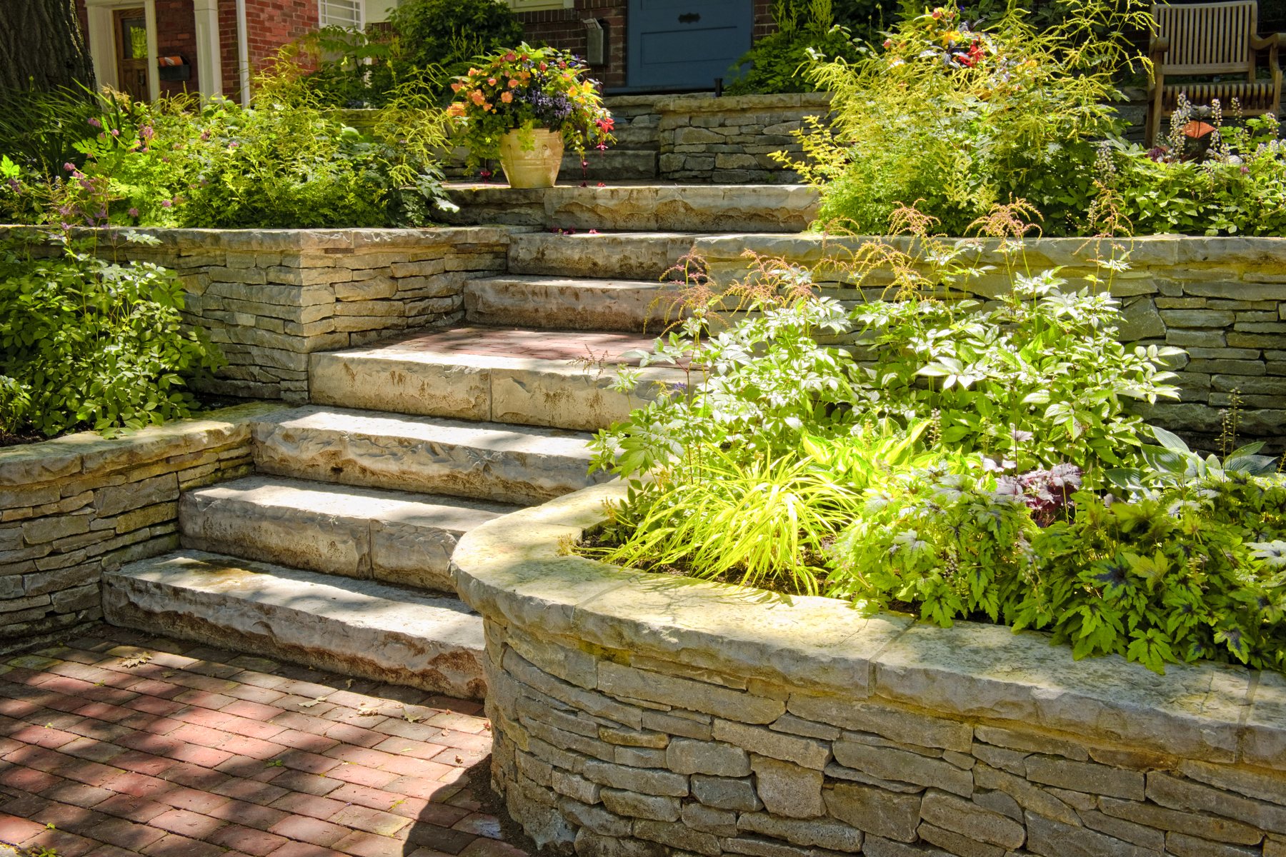Natursteinmauer mit Gräsern und Bepflanzung in einem Garten